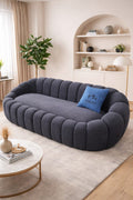 Modern living room with a gray tufted sofa, round coffee table, and decorative items.