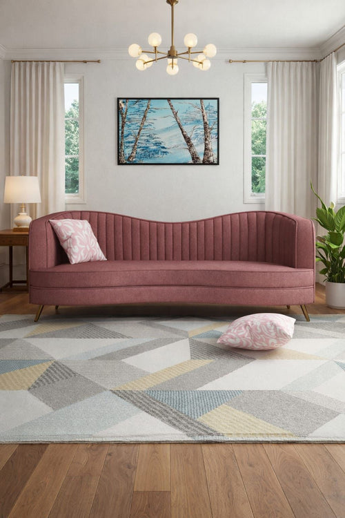 Living room with a pink sofa, geometric rug, and framed artwork on the wall.