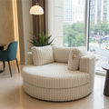 A round, cream-colored corduroy lounge chair with matching pillows, positioned in a modern living room setting with a large window showing a city view.