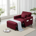 A burgundy upholstered reclining sofa with an ottoman footrest, shown in a bright modern room with large windows, plants, and a light rug. The sofa includes built-in cup holders and side controls, with a light blue throw blanket draped over the ottoman.