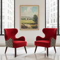 Two red wingback armchairs with black-and-white chevron patterned side panels are placed in a bright room with large windows and a framed landscape painting on the wall.