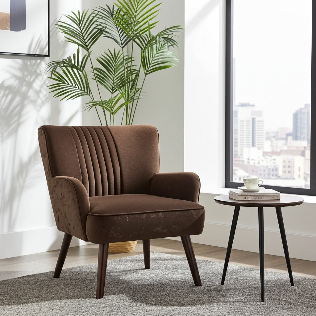 A brown upholstered accent chair with vertical channel tufting on the backrest, shown in a modern living room setting next to a small round side table and a potted palm plant.