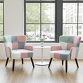 Two matching patchwork armchairs in pastel pink, blue, mint green, and white, positioned on either side of a small white round table in a bright room with large windows.