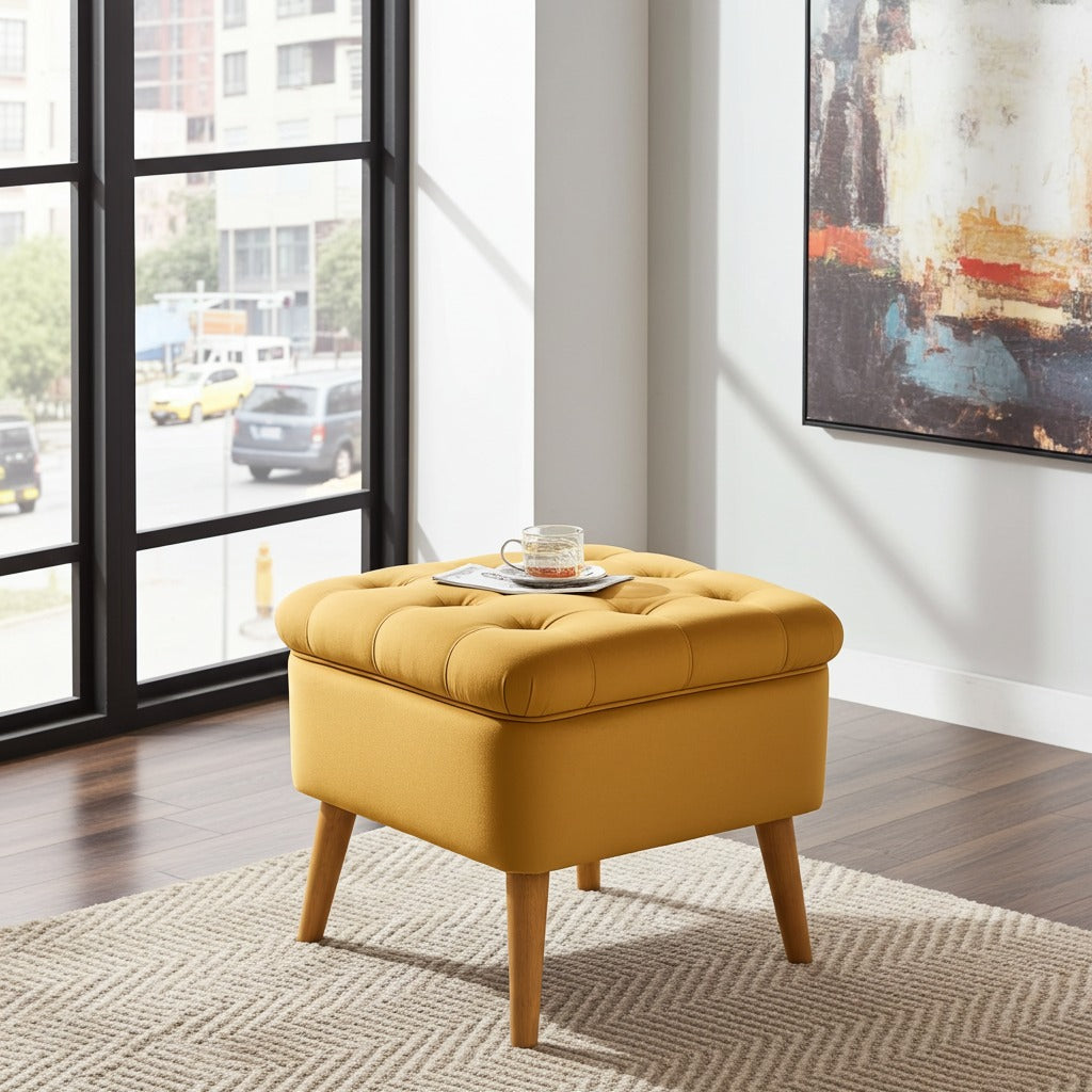 A mustard yellow tufted storage ottoman with wooden legs sits on a textured rug in a modern living room setting with a window and abstract wall art.