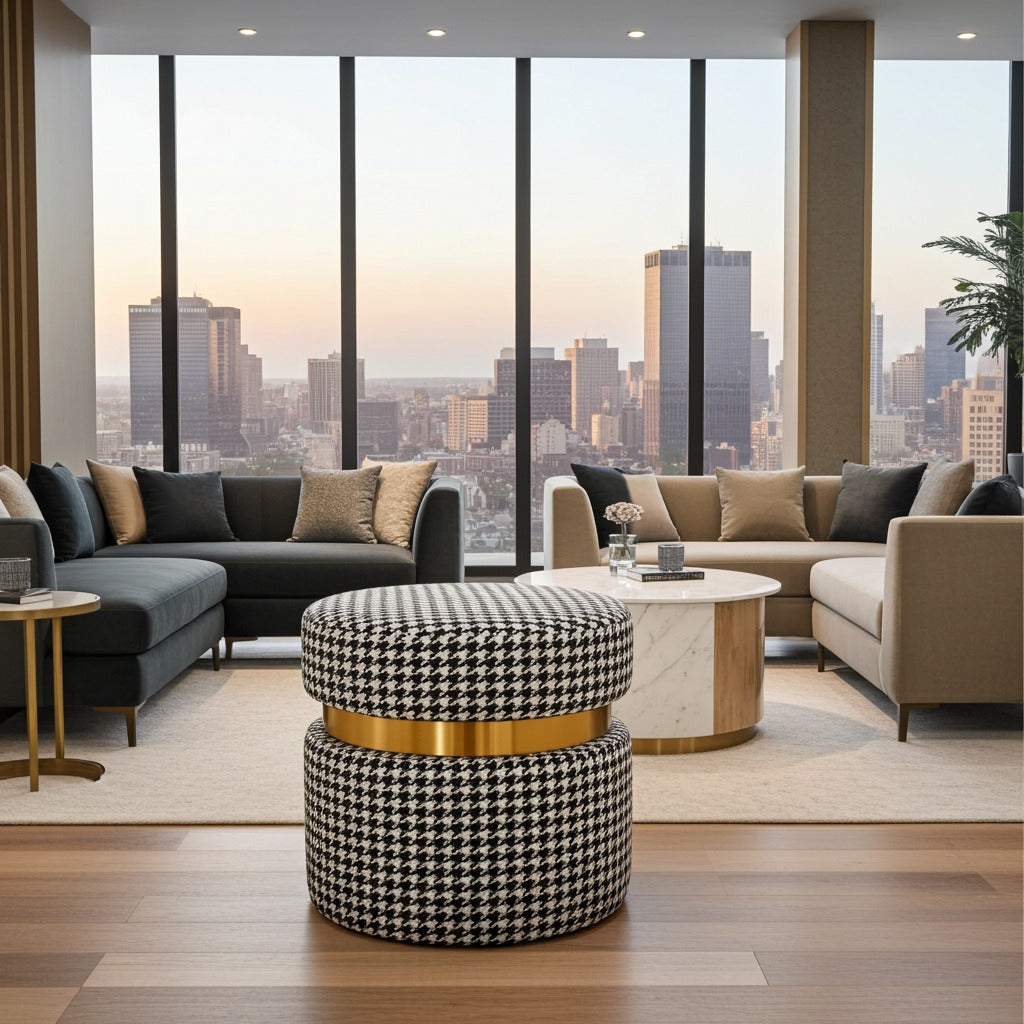 A modern living room with a black and white houndstooth ottoman in the foreground, flanked by dark gray and beige sofas, set against a large window view of a city skyline at sunset.