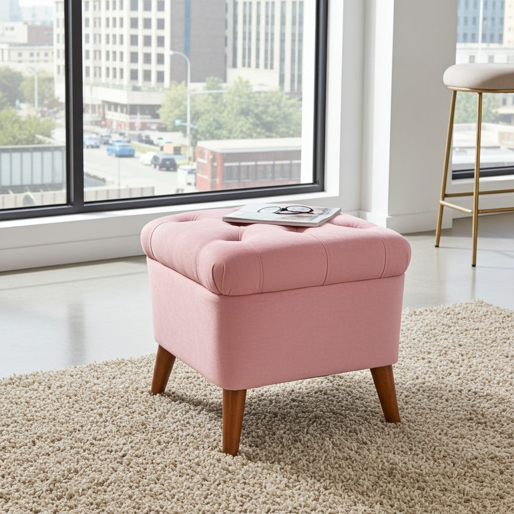 A pink upholstered storage ottoman with a tufted lid and tapered wooden legs, placed on a beige shag rug in a bright room with a large window and a magazine resting on top.