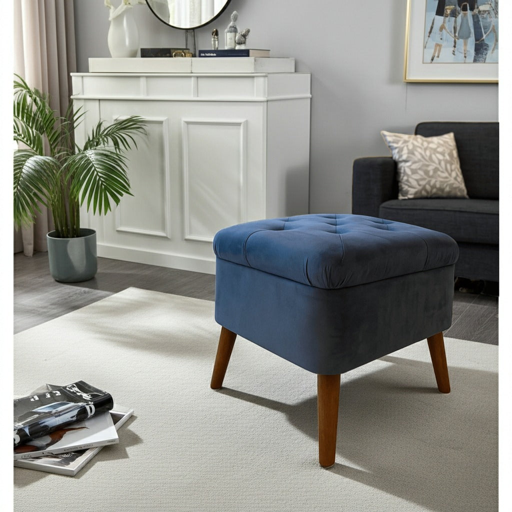 A blue tufted velvet storage ottoman with tapered wooden legs, styled in a modern living room setting.
