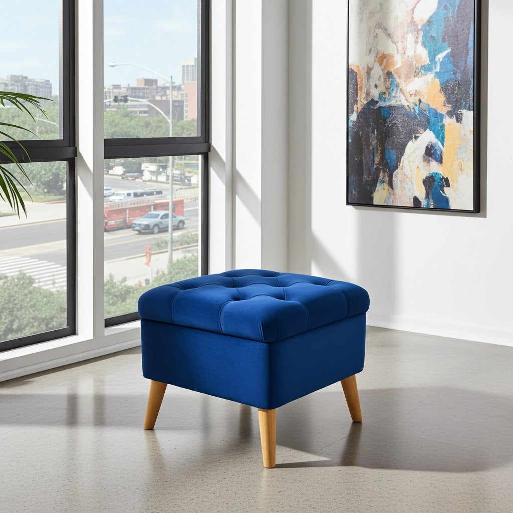 A blue tufted storage ottoman with light wood legs, positioned in a modern room next to a large window with an outdoor view.