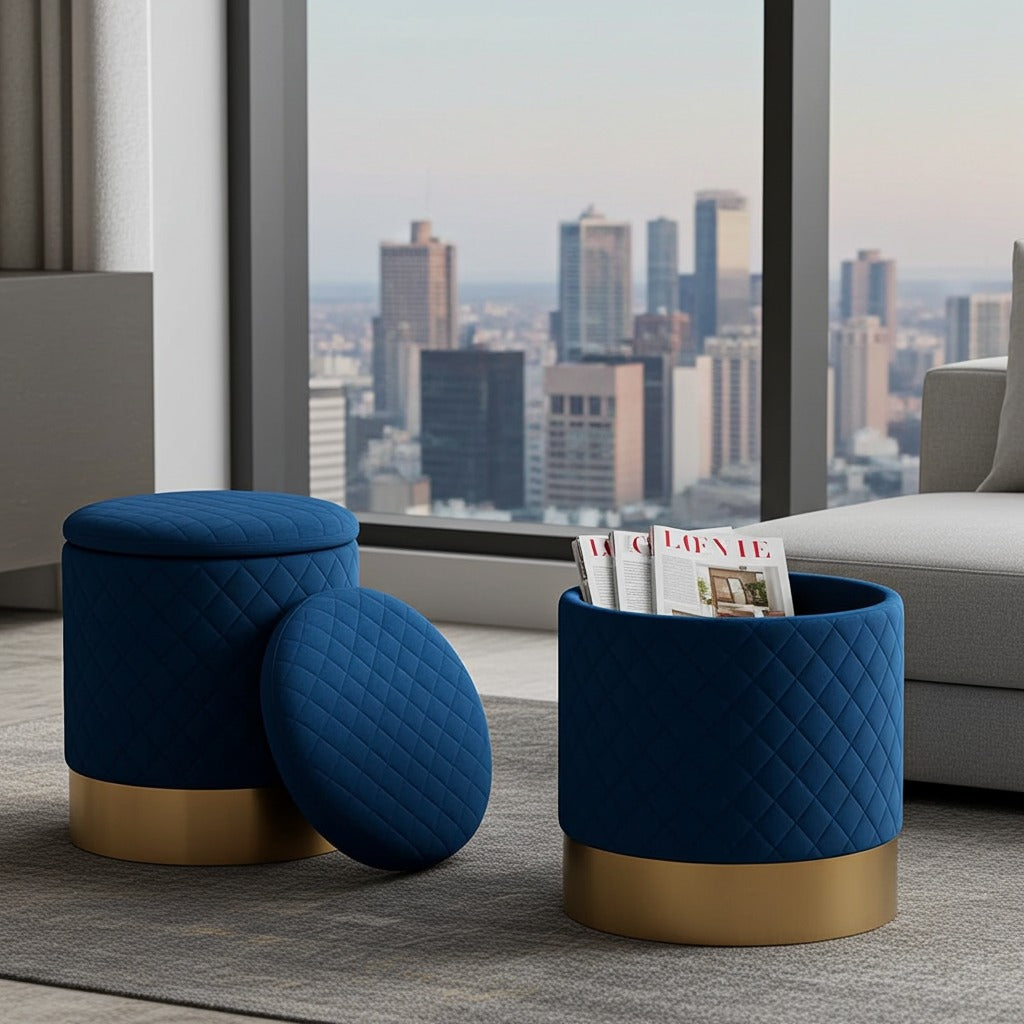 Two navy blue quilted cylindrical ottomans with gold bases in a modern living room setting, with one standing and one leaning, next to a matching cylindrical bin filled with magazines.