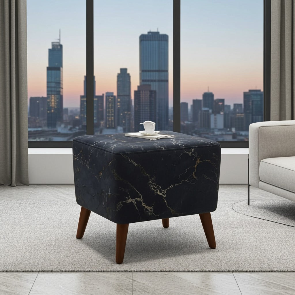 A square ottoman with a black marble pattern and tapered wooden legs, styled in a modern living room setting with a city skyline view in the background.