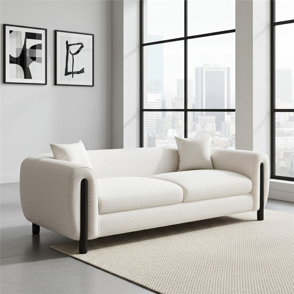 A modern cream bouclé loveseat sofa with black legs, styled in a bright contemporary room with a city view window background.