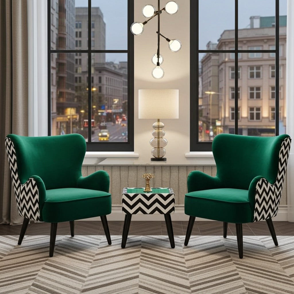 Two emerald green velvet wingback armchairs with black-and-white chevron patterned side panels, arranged around a matching side table in a modern living room setting with large windows overlooking a city street.