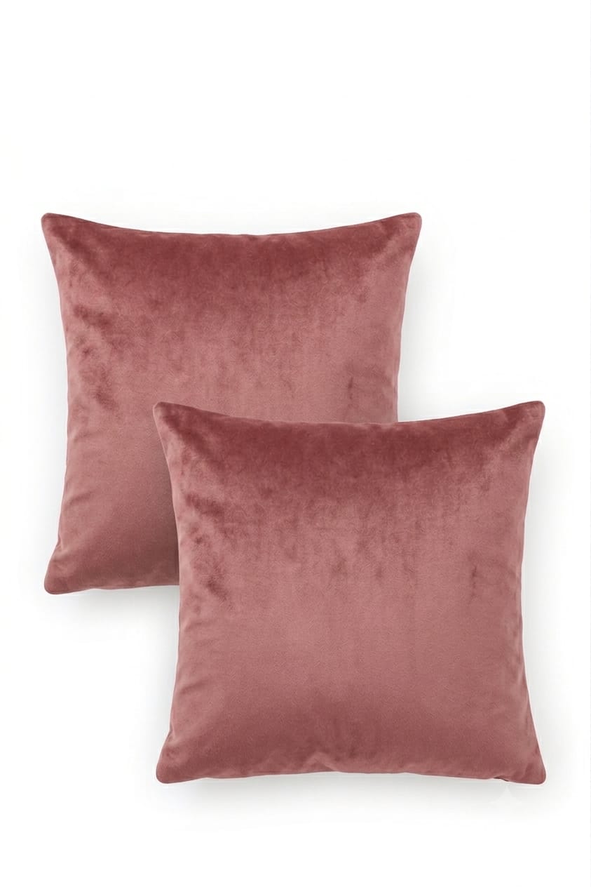 Two square velvet throw pillows in a dusty rose pink color, arranged overlapping on a clean white background.