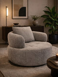 Gray armchair in a cozy living room setting with a lamp, plant, and side table.