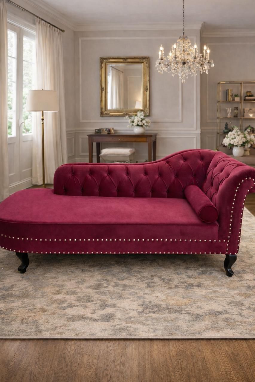 Magenta velvet chaise lounge in a stylish room with a mirror, lamp, and decor.