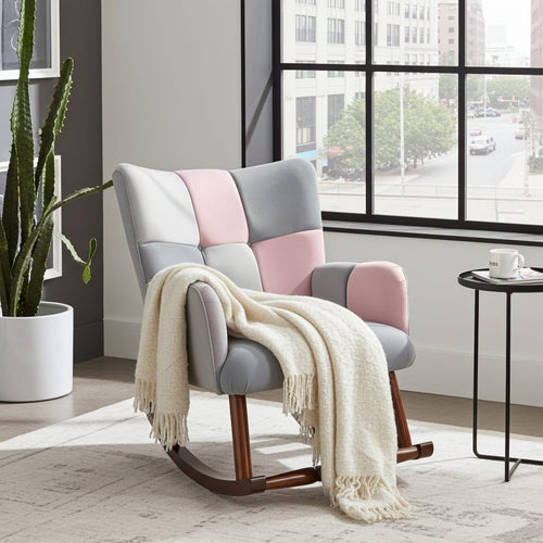 A modern rocking armchair with patchwork upholstery in light gray, blush pink, and off-white, with dark wood rockers. A cream throw blanket is draped over the chair in a bright, contemporary room with a large window, a potted cactus, and a small side table.
