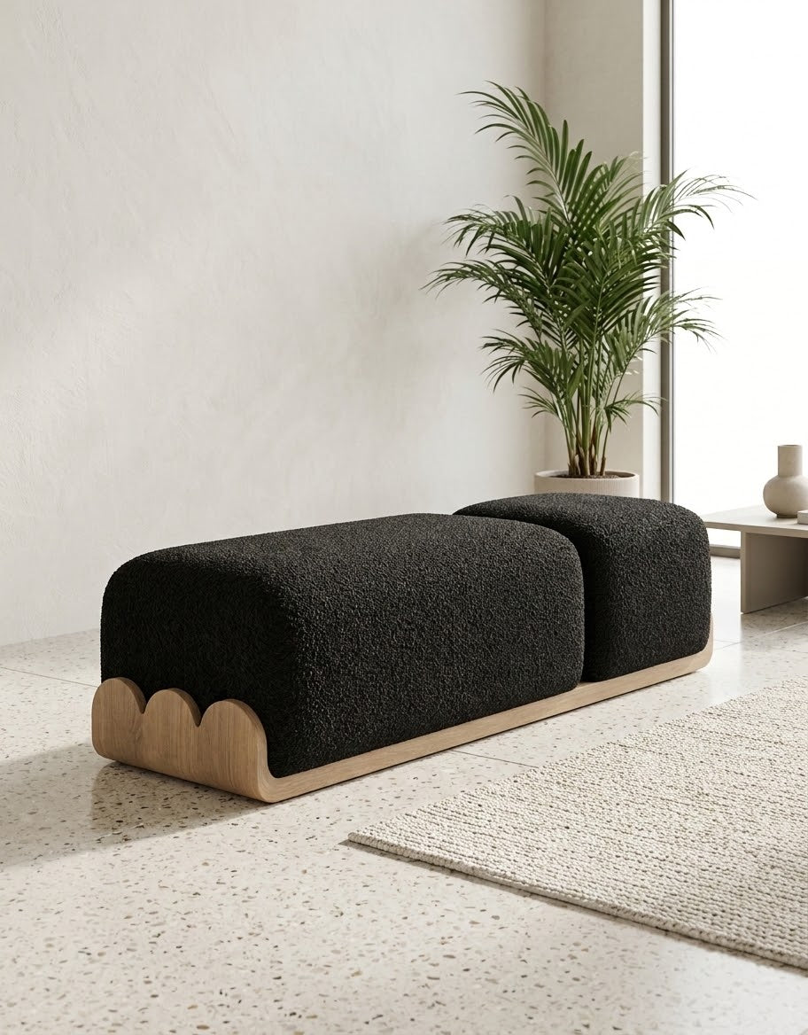 A modern two-seat bench with a black bouclé upholstered seat and a light natural wood base featuring scalloped edges, set in a minimalist room with a potted plant and textured rug.