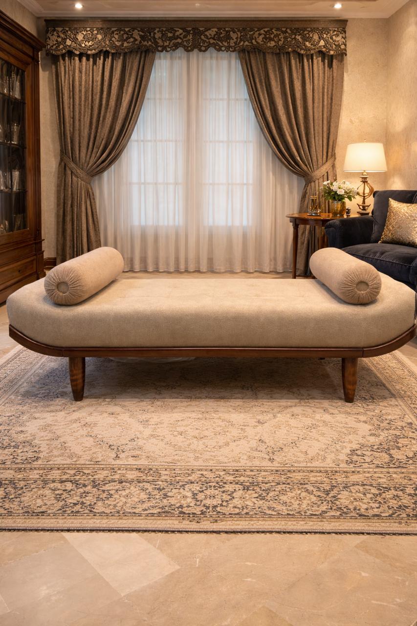 Decorative daybed with pillows in a room with curtains and a lamp.