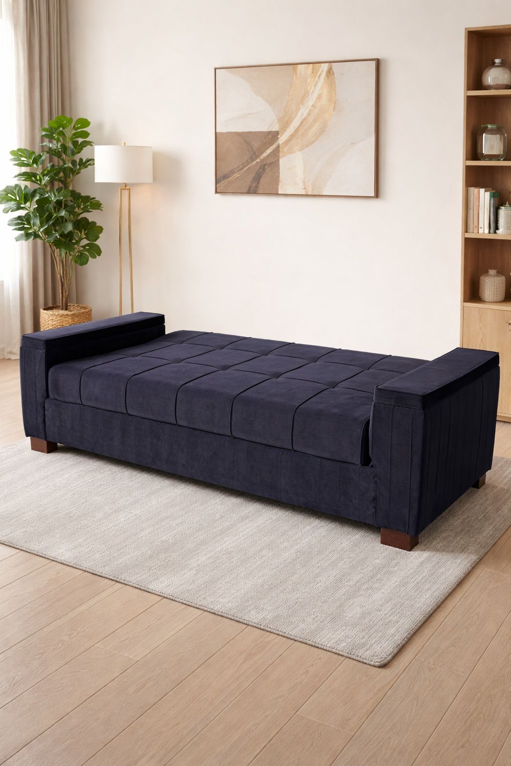 Navy blue sofa bed in a room with a lamp, plant, and wall art.