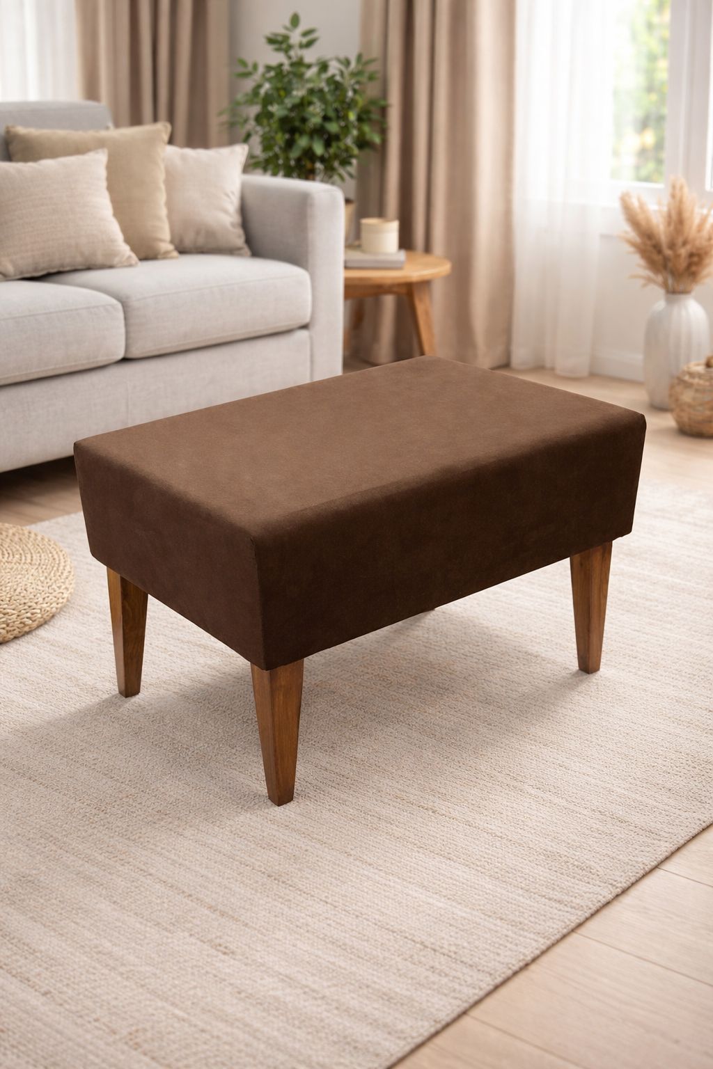 Brown ottoman in a living room setting with a sofa and decor items.