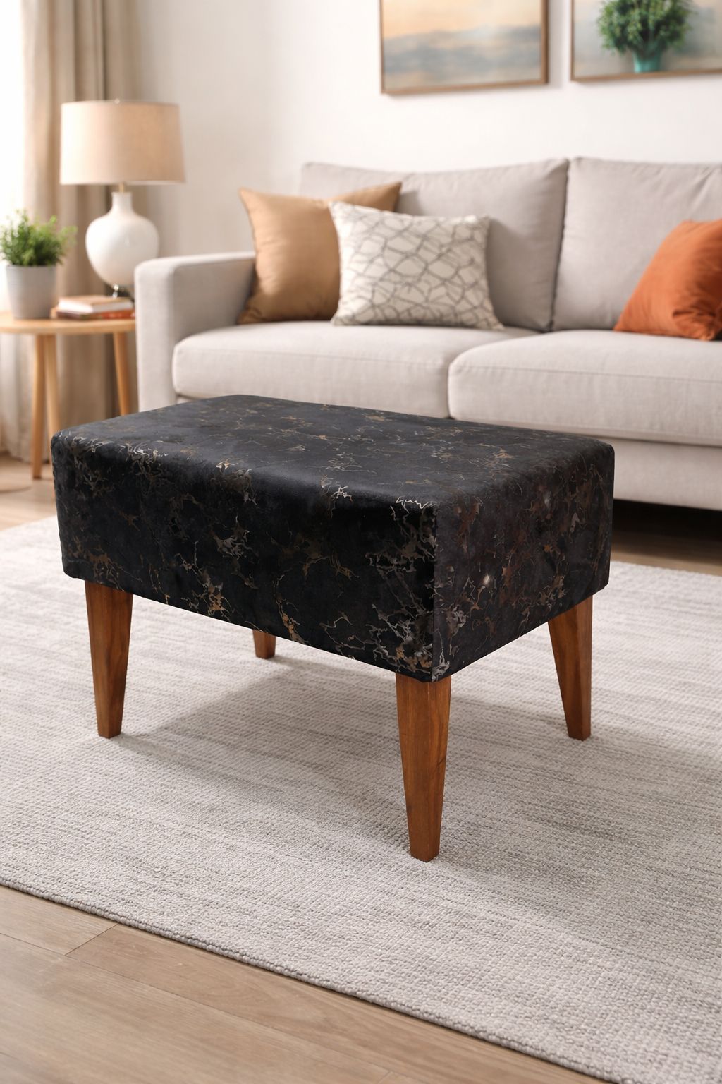 Black ottoman with wooden legs in a living room setting